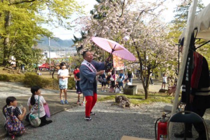 祭りの境内で太神楽の演技を披露する芸人「かがみもち」